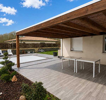 Pergola en bois sur mesure installée sur une terrasse moderne dans un jardin aménagé