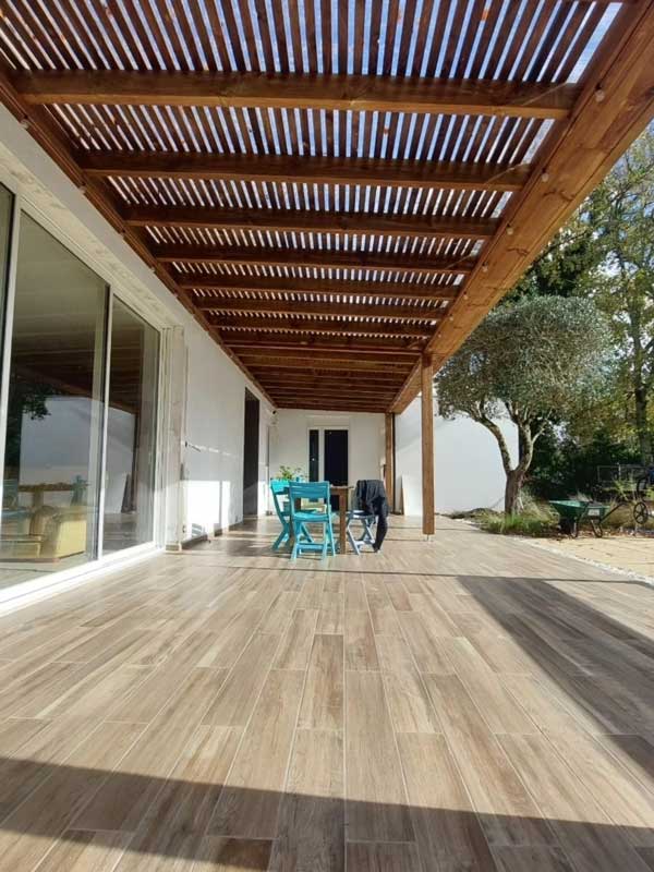Grande terrasse carrelée couverte par une pergola en bois à claire-voie